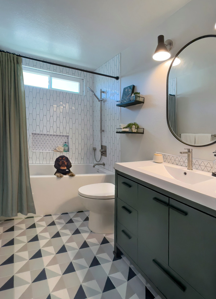 Photo of a medium sized retro shower room bathroom in Orange County with flat-panel cabinets, green cabinets, an alcove bath, a shower/bath combination, a one-piece toilet, white tiles, porcelain tiles, grey walls, porcelain flooring, a submerged sink, engineered stone worktops, multi-coloured floors, a shower curtain, white worktops, a single sink and a built in vanity unit.
