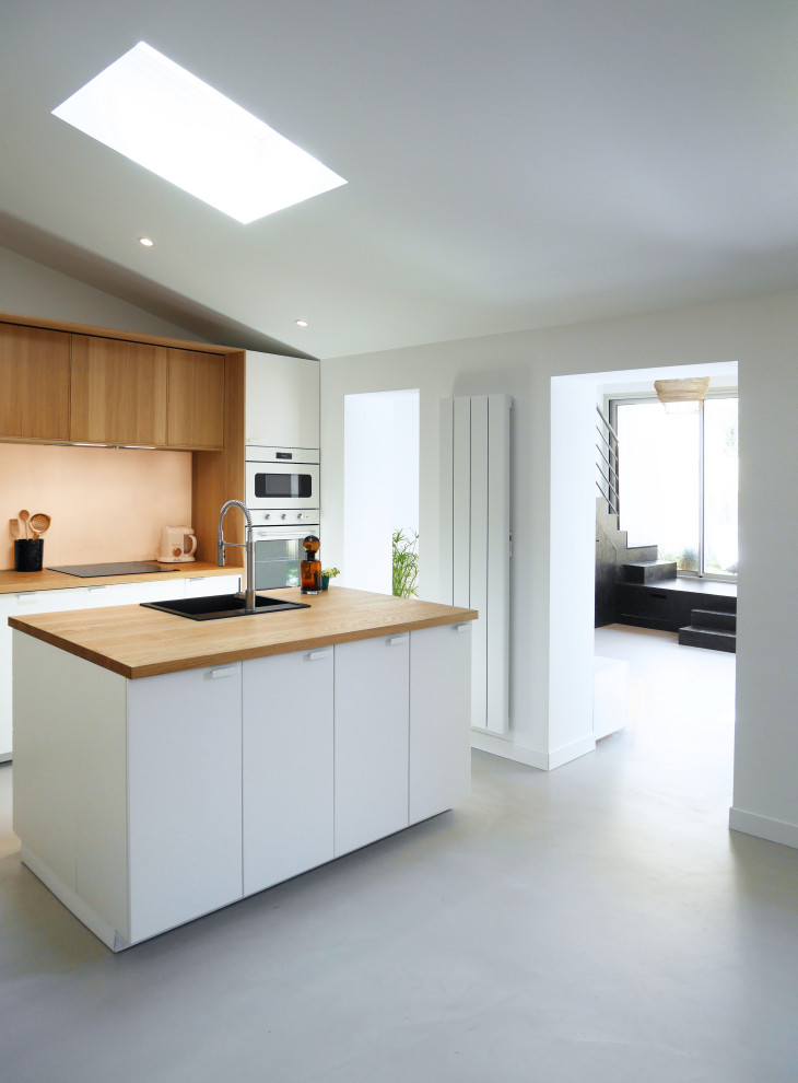 Design ideas for a large contemporary single-wall open plan kitchen with a single-bowl sink, beaded inset cabinets, white cabinets, wood benchtops, pink splashback, glass sheet splashback, panelled appliances, concrete floors, with island, grey floor and brown benchtop.