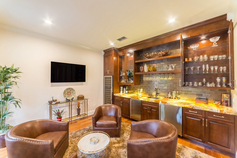 This is an example of a mid-sized traditional single-wall wet bar in Orlando with an undermount sink, raised-panel cabinets, medium wood cabinets, onyx benchtops, porcelain splashback, medium hardwood floors, brown floor and yellow benchtop.