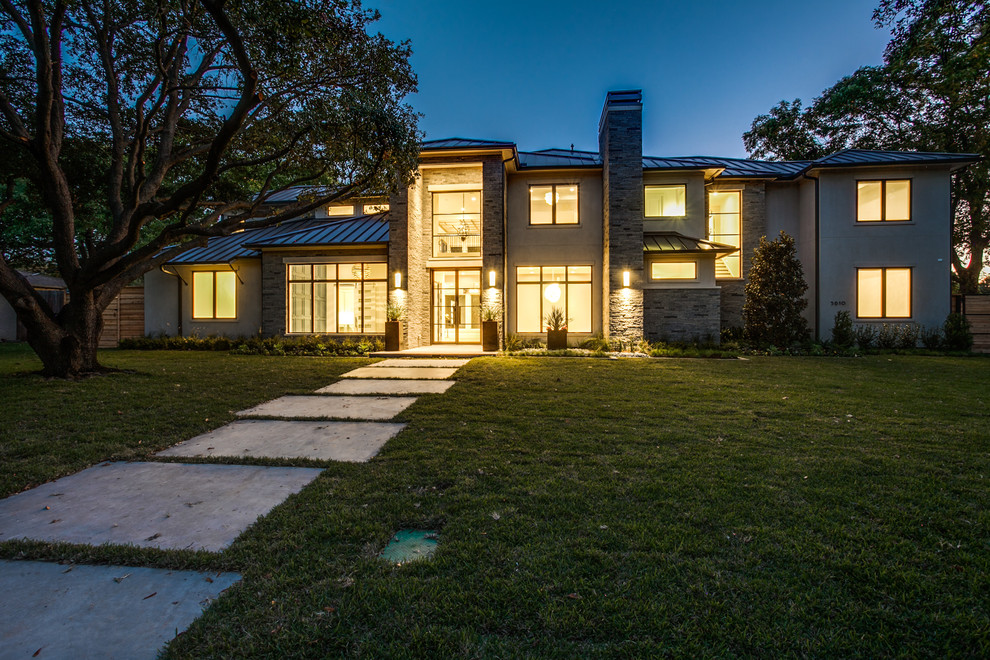 Large modern two-storey white house exterior in Dallas with stone veneer, a hip roof and a metal roof.