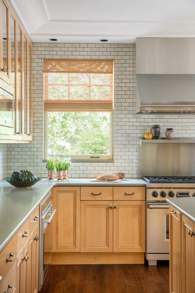 Bild på ett mellanstort vintage grön grönt kök, med en dubbel diskho, luckor med profilerade fronter, skåp i ljust trä, bänkskiva i kvarts, brunt stänkskydd, stänkskydd i keramik, rostfria vitvaror, mörkt trägolv, en köksö och brunt golv