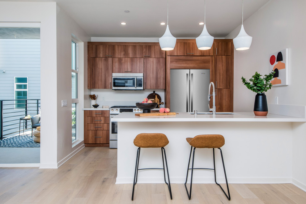 Inspiration for a contemporary galley open plan kitchen in Los Angeles with flat-panel cabinets, dark wood cabinets, quartzite benchtops, stainless steel appliances, no island and white benchtop.