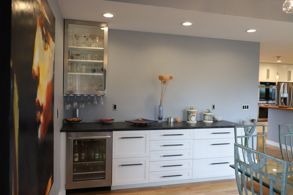 Mid-sized transitional u-shaped medium tone wood floor and brown floor eat-in kitchen photo with shaker cabinets, white cabinets, granite countertops, blue backsplash, stainless steel appliances, black countertops, an undermount sink, stone tile backsplash and a peninsula