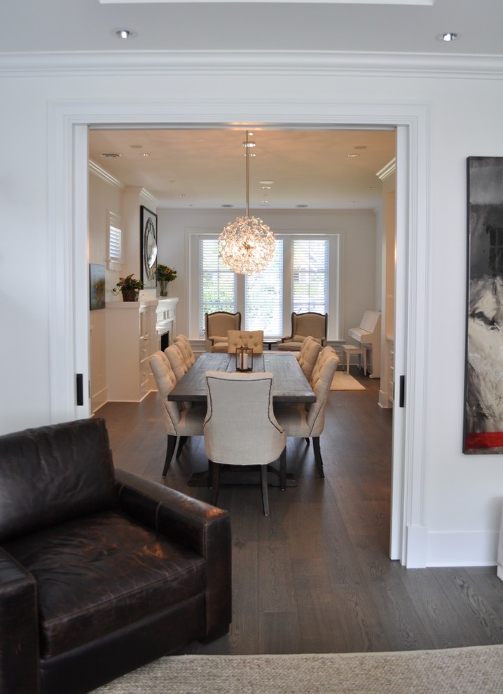 Photo of a transitional dining room in Vancouver with white walls, dark hardwood floors and a stone fireplace surround.