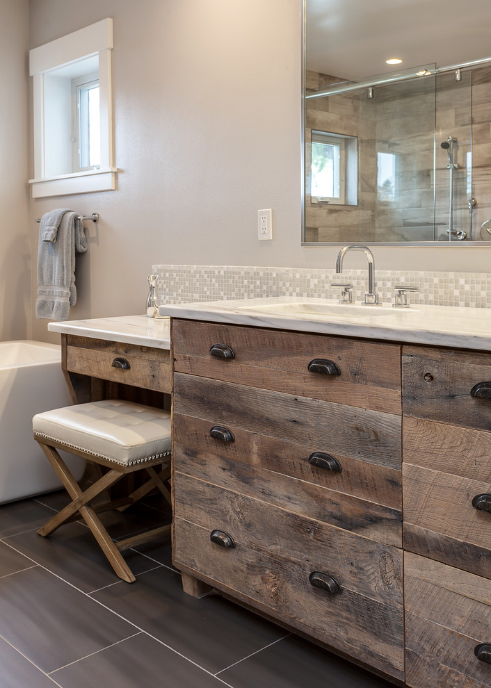 Photo of an expansive contemporary master bathroom in Denver with flat-panel cabinets, distressed cabinets, a freestanding tub, an open shower, beige tile, ceramic tile, grey walls, medium hardwood floors, an undermount sink and granite benchtops.