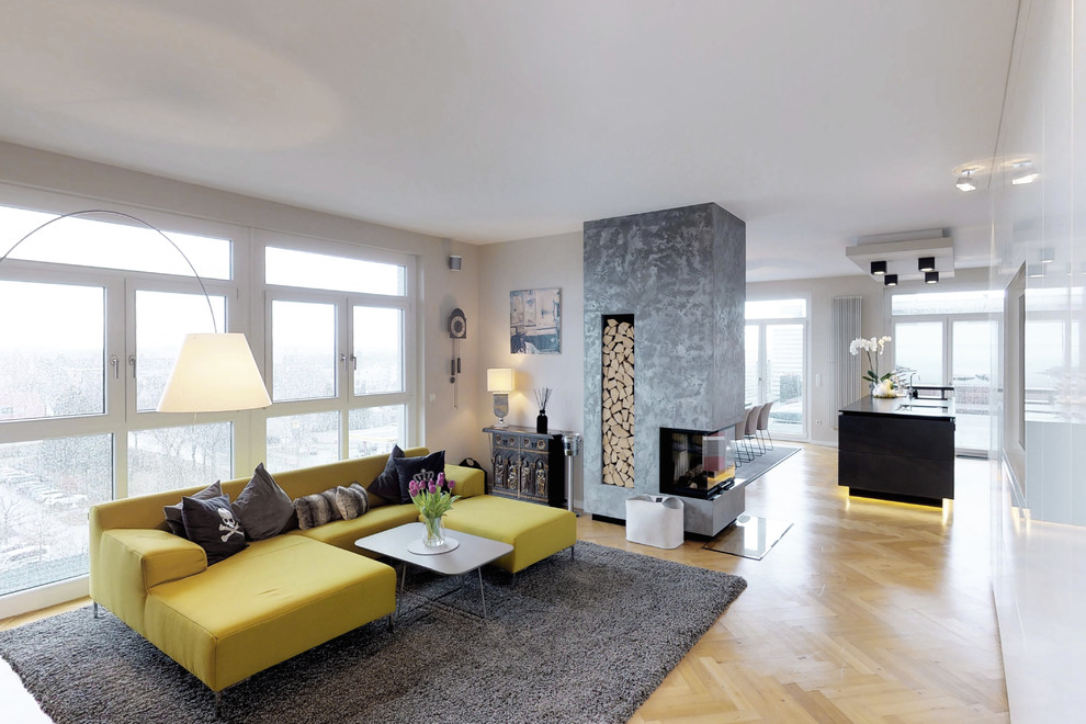 This is an example of a large contemporary formal loft-style living room in Nuremberg with beige walls, a two-sided fireplace, a wall-mounted tv, beige floor and light hardwood floors.