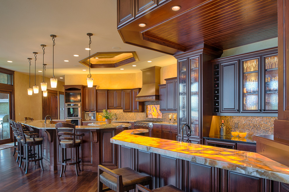 This is an example of a traditional eat-in kitchen in Minneapolis with raised-panel cabinets, dark wood cabinets, mosaic tile splashback, stainless steel appliances, dark hardwood floors and multiple islands.