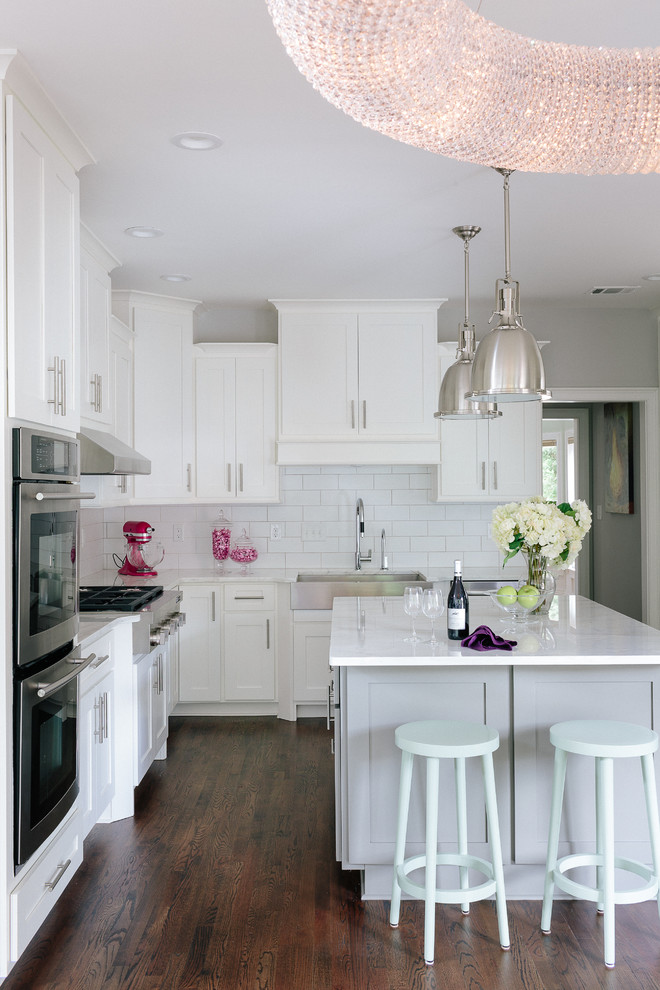 Example of a large transitional u-shaped dark wood floor eat-in kitchen design in Atlanta with a farmhouse sink, shaker cabinets, white cabinets, marble countertops, white backsplash, ceramic backsplash, stainless steel appliances and an island