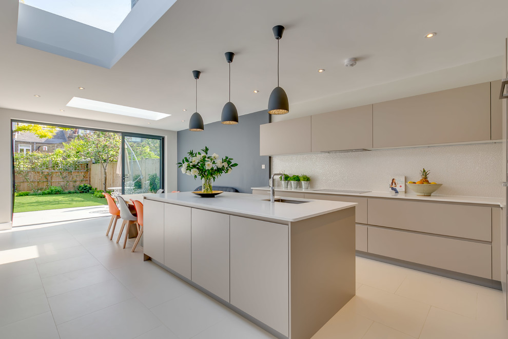 Large contemporary galley open plan kitchen in London with flat-panel cabinets, granite benchtops, with island, white benchtop, beige cabinets, beige floor, an undermount sink and beige splashback.