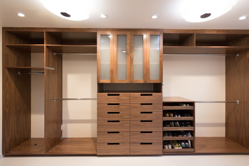 Inspiration for a large contemporary gender-neutral walk-in wardrobe in San Francisco with flat-panel cabinets, dark wood cabinets, porcelain floors and white floor.