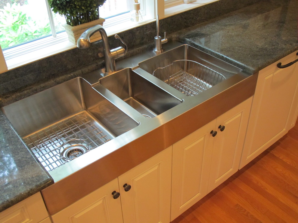 Traditional kitchen in Chicago with a triple-bowl sink, raised-panel cabinets and white cabinets.