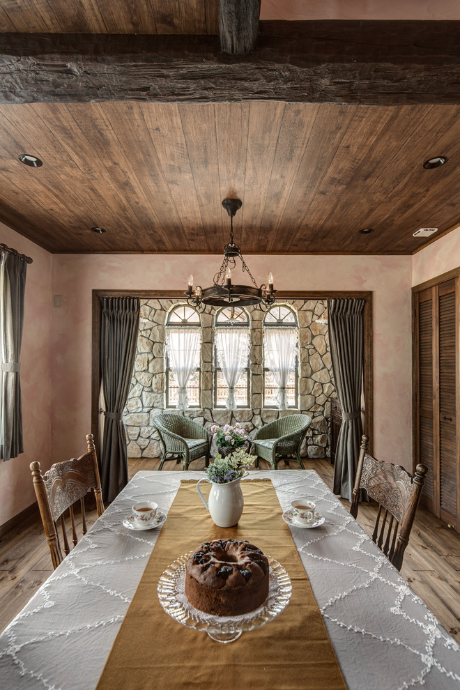 This is an example of a traditional dining room in Other with pink walls, medium hardwood floors and brown floor.