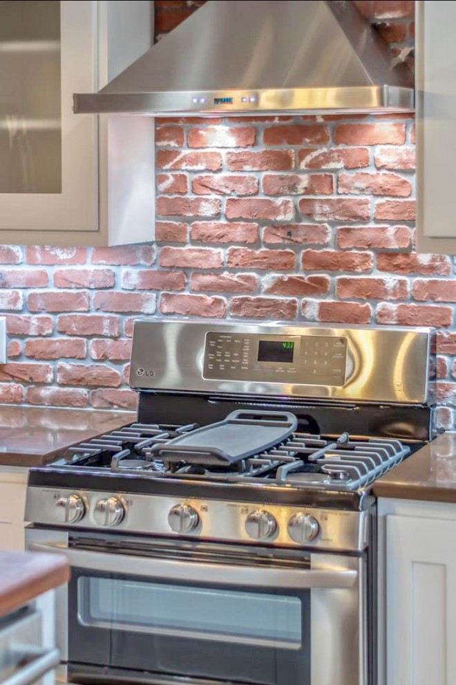 Example of a large transitional u-shaped terra-cotta tile and beige floor enclosed kitchen design in Austin with a drop-in sink, shaker cabinets, white cabinets, granite countertops, red backsplash, brick backsplash, stainless steel appliances, an island and gray countertops