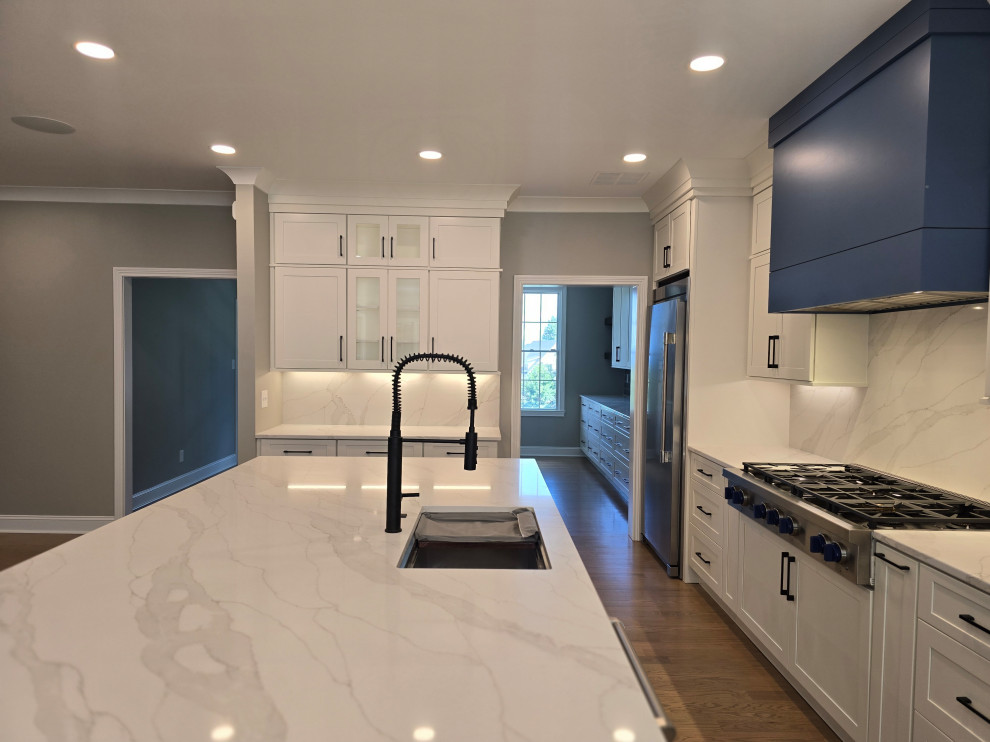 Inspiration for a large modern l-shaped medium tone wood floor and brown floor kitchen remodel with an undermount sink, shaker cabinets, white cabinets, quartz countertops, gray backsplash, subway tile backsplash, stainless steel appliances, an island and white countertops