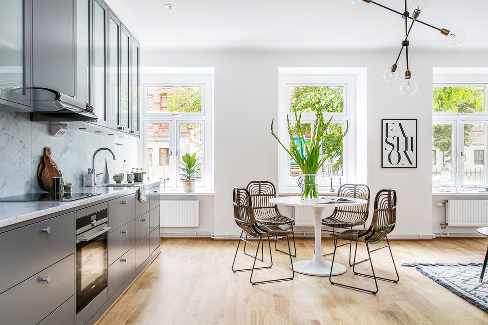 This is an example of a large scandinavian open plan dining in Stockholm with white walls and light hardwood floors.