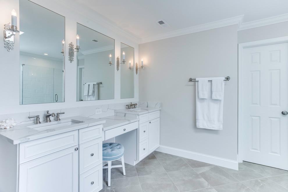 Photo of a transitional master bathroom in DC Metro with shaker cabinets, white cabinets, a drop-in tub, a two-piece toilet, white tile, ceramic tile, porcelain floors, an undermount sink, engineered quartz benchtops, brown floor, a hinged shower door and white benchtops.