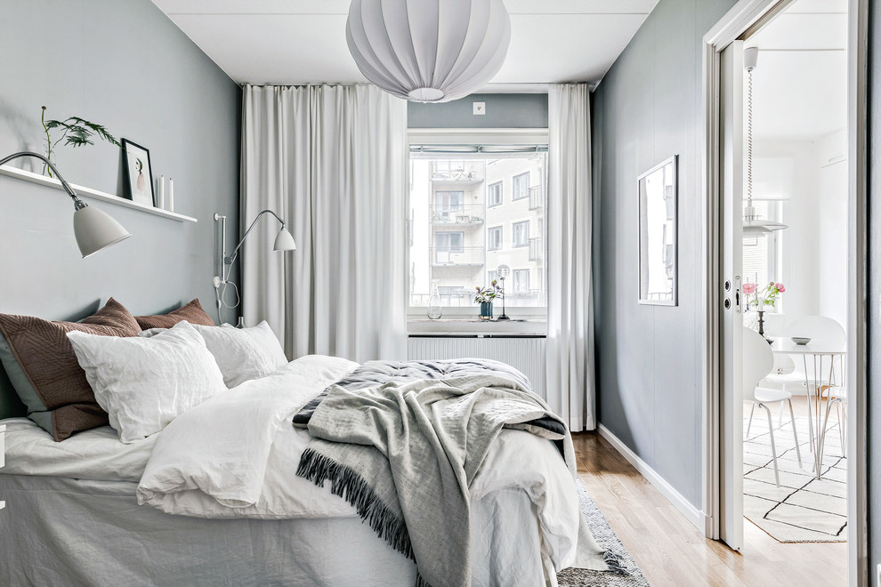 Small scandinavian guest bedroom in Gothenburg with grey walls, light hardwood floors and beige floor.