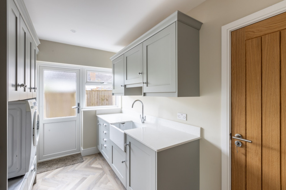 This is an example of a large modern l-shaped open plan kitchen in Sussex with shaker cabinets, grey cabinets, quartz worktops, an island and white worktops.