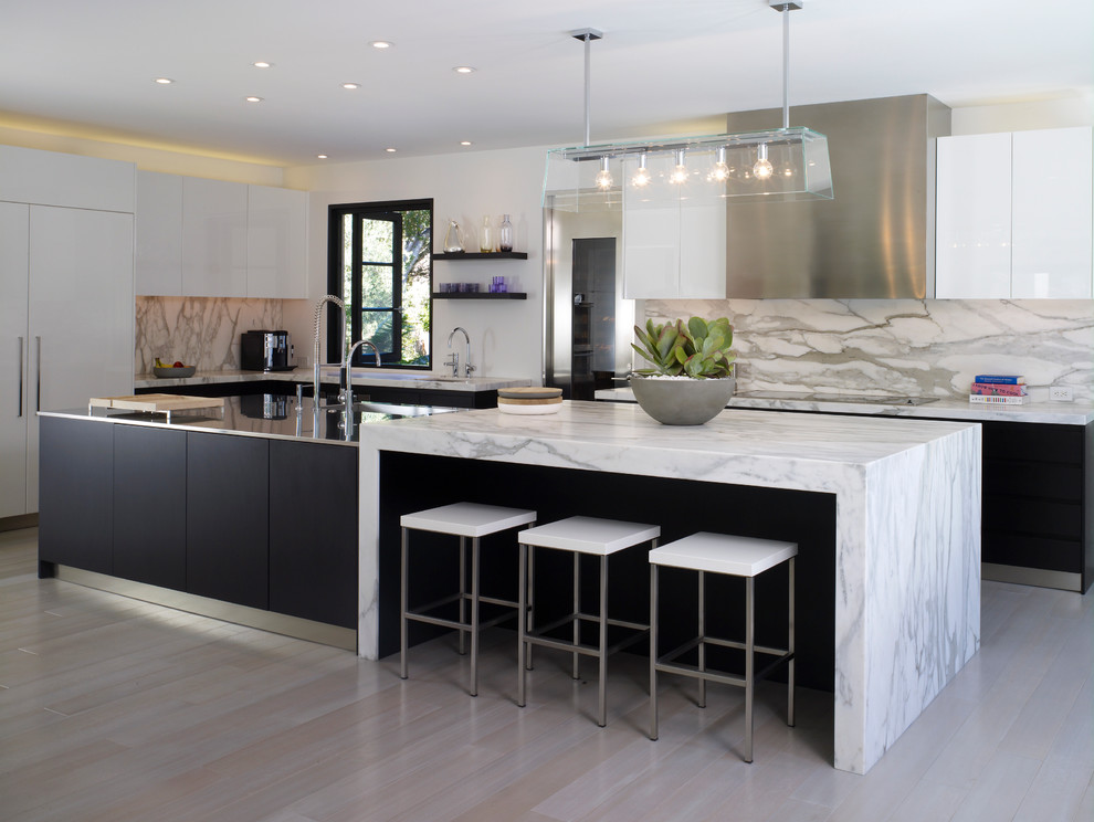 Design ideas for a large contemporary l-shaped kitchen in Los Angeles with an integrated sink, flat-panel cabinets, white cabinets, stainless steel benchtops, panelled appliances, with island, grey splashback, marble splashback and light hardwood floors.