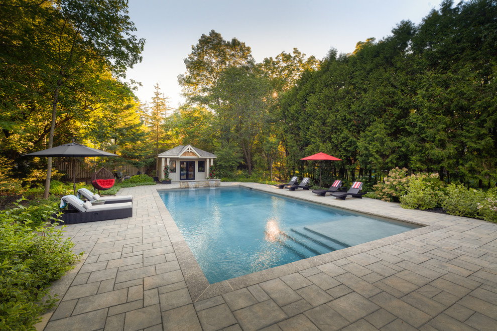 Large traditional backyard pool in Toronto with concrete pavers.