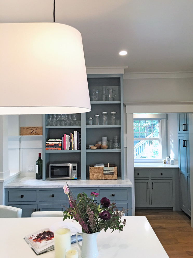Inspiration for a mid-sized arts and crafts u-shaped kitchen pantry in San Francisco with a farmhouse sink, shaker cabinets, grey cabinets, marble benchtops, white splashback, timber splashback, stainless steel appliances, light hardwood floors, with island and brown floor.