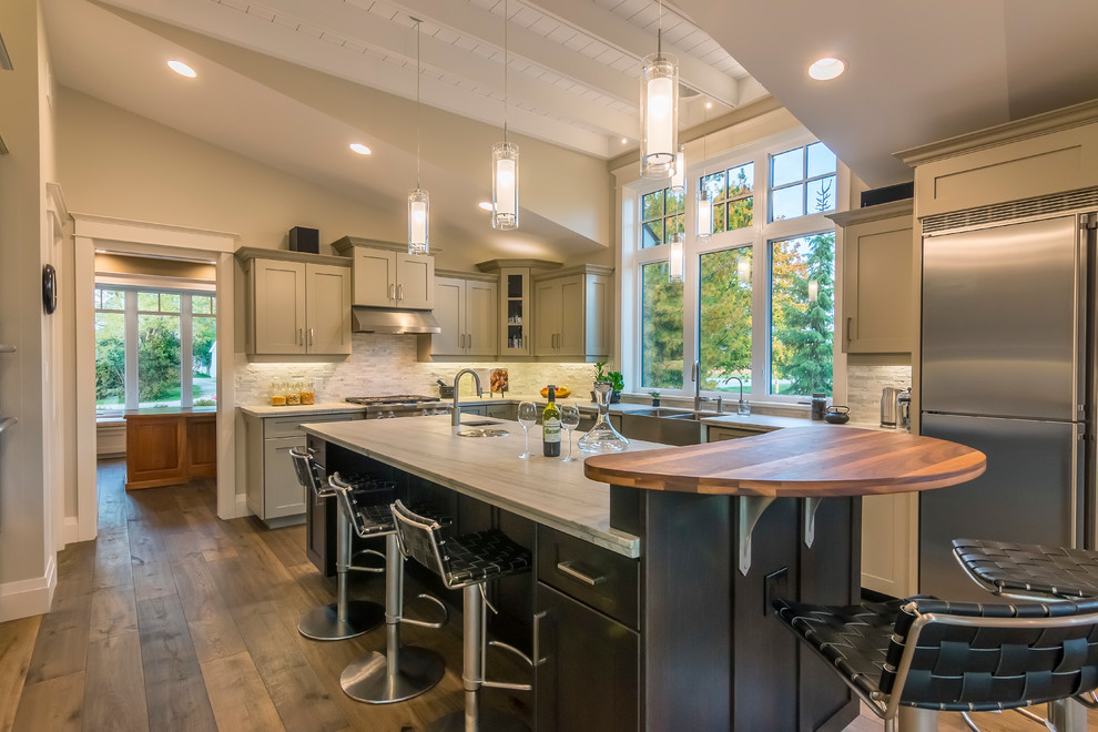 Large arts and crafts u-shaped eat-in kitchen in Toronto with a farmhouse sink, shaker cabinets, grey cabinets, granite benchtops, white splashback, stone tile splashback, stainless steel appliances, dark hardwood floors and with island.