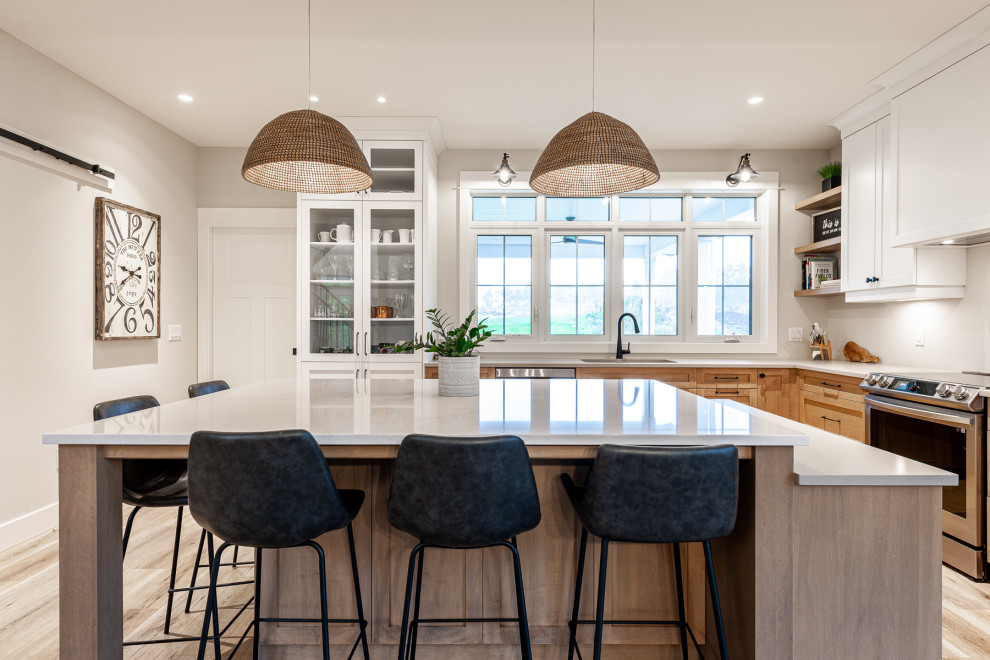 Mid-sized transitional l-shaped laminate floor and brown floor eat-in kitchen photo in Toronto with an undermount sink, recessed-panel cabinets, white cabinets, quartz countertops, stainless steel appliances, an island and white countertops