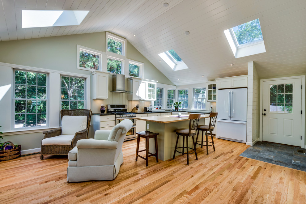 Eat-in kitchen - large transitional l-shaped light wood floor eat-in kitchen idea in Boston with shaker cabinets, white cabinets, a farmhouse sink, stainless steel appliances, quartzite countertops and an island