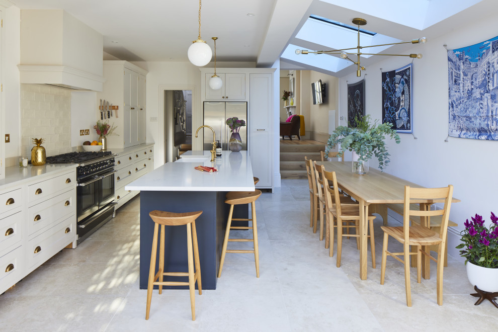 Large traditional l-shaped kitchen/diner in Surrey with a built-in sink, beaded cabinets, quartz worktops, black appliances, an island and white worktops.