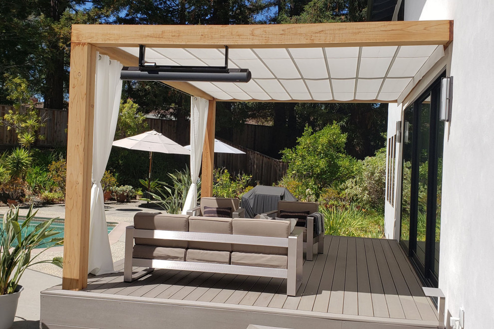Photo of a beach style backyard and ground level deck in San Francisco with a pergola.