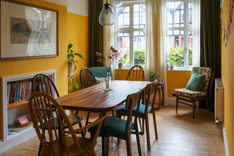 Inspiration pour une salle à manger traditionnelle avec un mur jaune, un sol en bois brun et un sol marron.