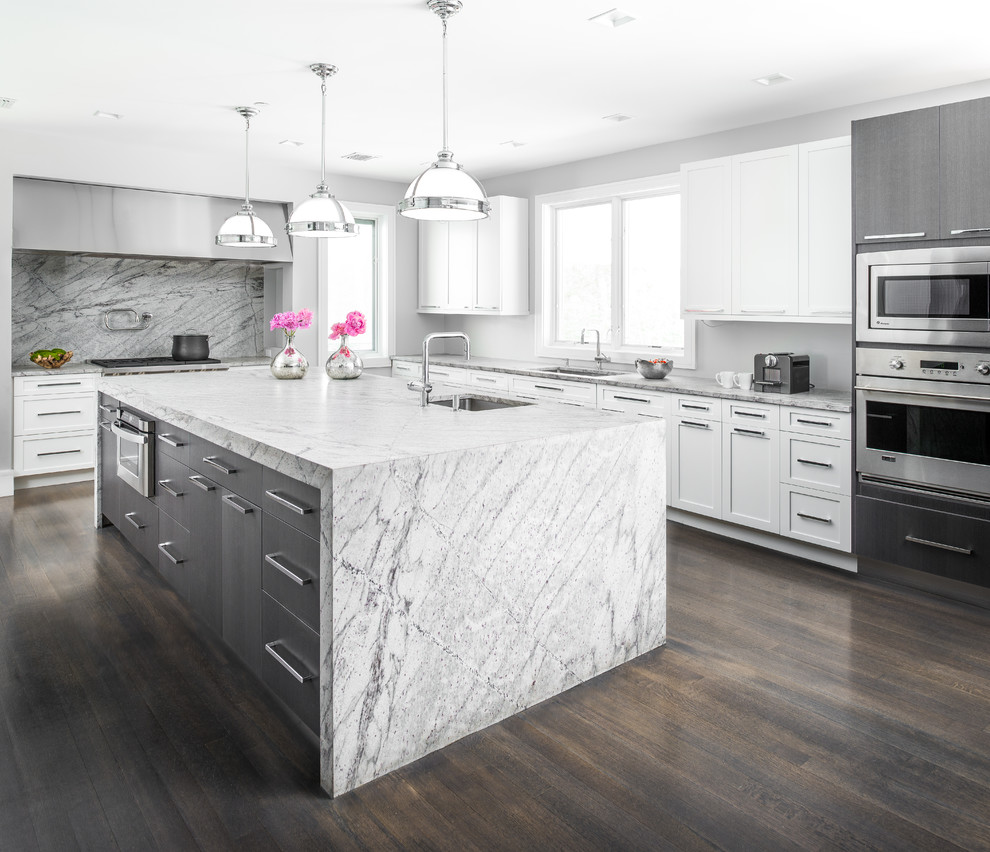 This is an example of a large contemporary l-shaped separate kitchen in New York with with island, a drop-in sink, flat-panel cabinets, white cabinets, marble benchtops, grey splashback, stainless steel appliances and plywood floors.