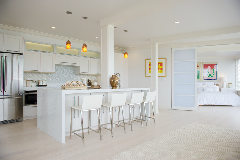 Example of a large trendy galley light wood floor open concept kitchen design in New York with shaker cabinets, white cabinets, gray backsplash, stainless steel appliances, an island, marble countertops, mosaic tile backsplash and an undermount sink