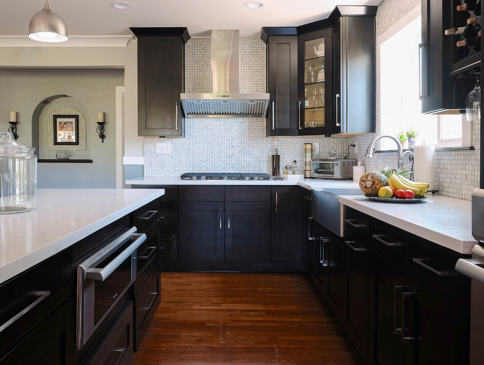 Photo of a large traditional galley eat-in kitchen in Los Angeles with a farmhouse sink, shaker cabinets, dark wood cabinets, quartz benchtops, multi-coloured splashback, ceramic splashback, stainless steel appliances, medium hardwood floors, brown floor and with island.