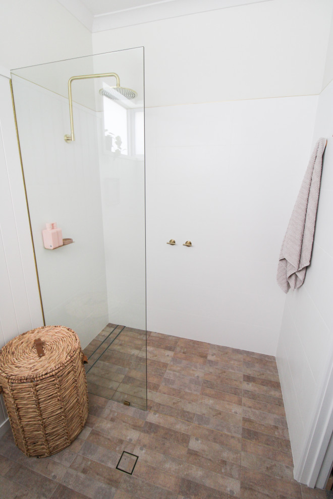 На фото: маленькая ванная комната в скандинавском стиле с плоскими фасадами, темными деревянными фасадами, открытым душем, унитазом-моноблоком, белой плиткой, керамической плиткой, белыми стенами, полом из керамогранита, душевой кабиной, настольной раковиной, столешницей из дерева, разноцветным полом, открытым душем, тумбой под одну раковину, подвесной тумбой и панелями на стенах для на участке и в саду