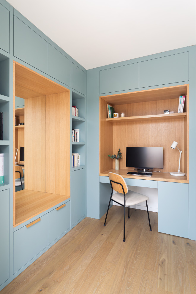Ejemplo de despacho escandinavo de tamaño medio sin chimenea con paredes azules, suelo de madera clara y escritorio empotrado