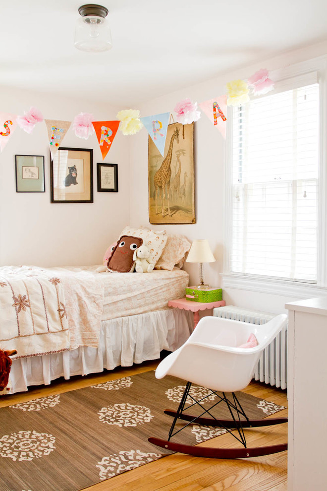 Photo of a transitional kids' room for girls in New York with white walls and medium hardwood floors.