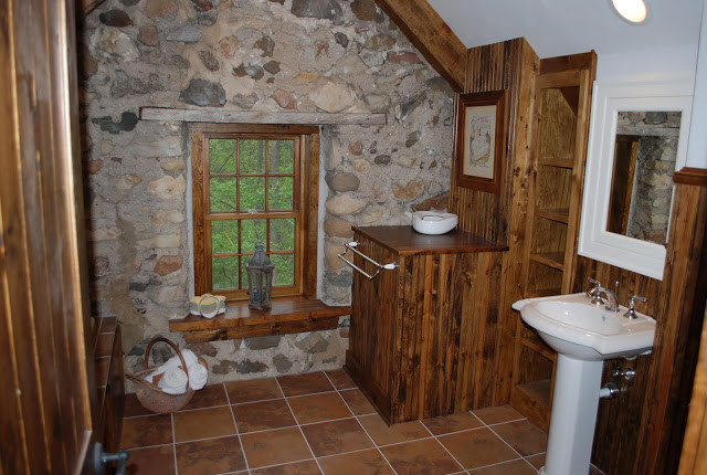 Mid-sized country 3/4 bathroom in Milwaukee with flat-panel cabinets, dark wood cabinets, a two-piece toilet, brown walls, terra-cotta floors, a pedestal sink, wood benchtops and brown floor.