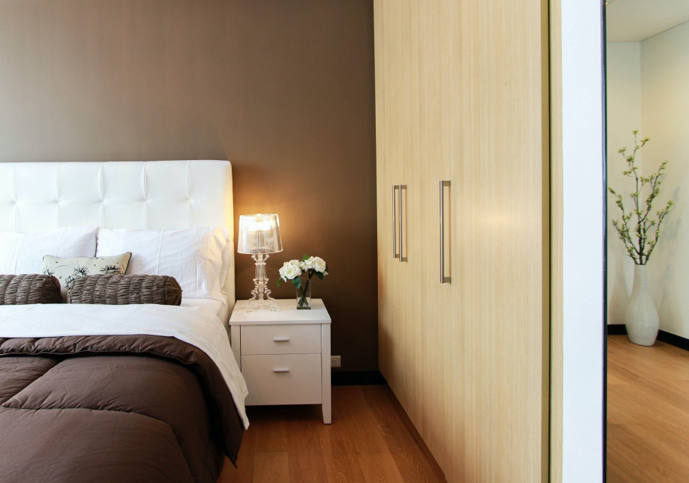 Immagine di una camera degli ospiti minimalista di medie dimensioni con pareti marroni, pavimento in legno massello medio e pavimento marrone