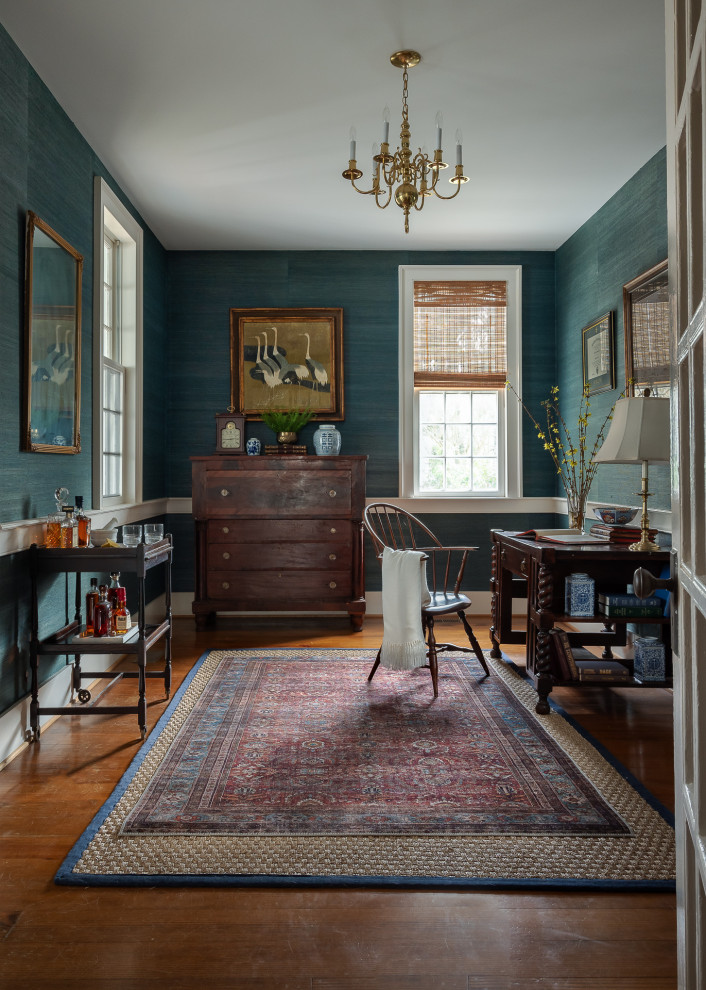 Photo of a traditional home office in Raleigh with wallpaper, blue walls, medium hardwood floors, a freestanding desk and brown floor.
