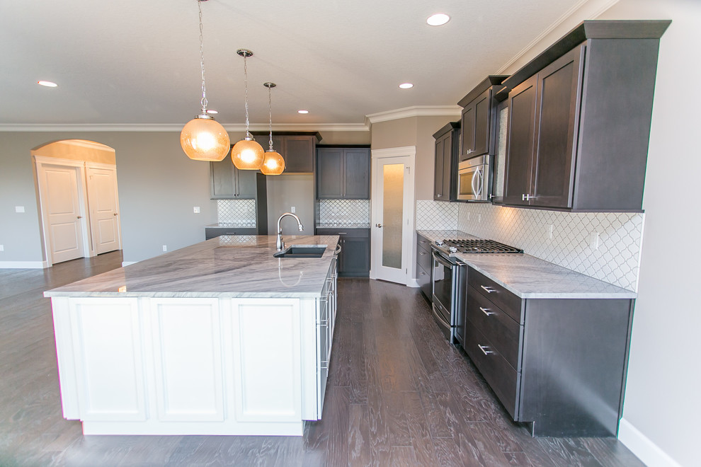Example of a mid-sized transitional l-shaped dark wood floor open concept kitchen design in Seattle with an undermount sink, shaker cabinets, dark wood cabinets, granite countertops, white backsplash, porcelain backsplash, stainless steel appliances and an island