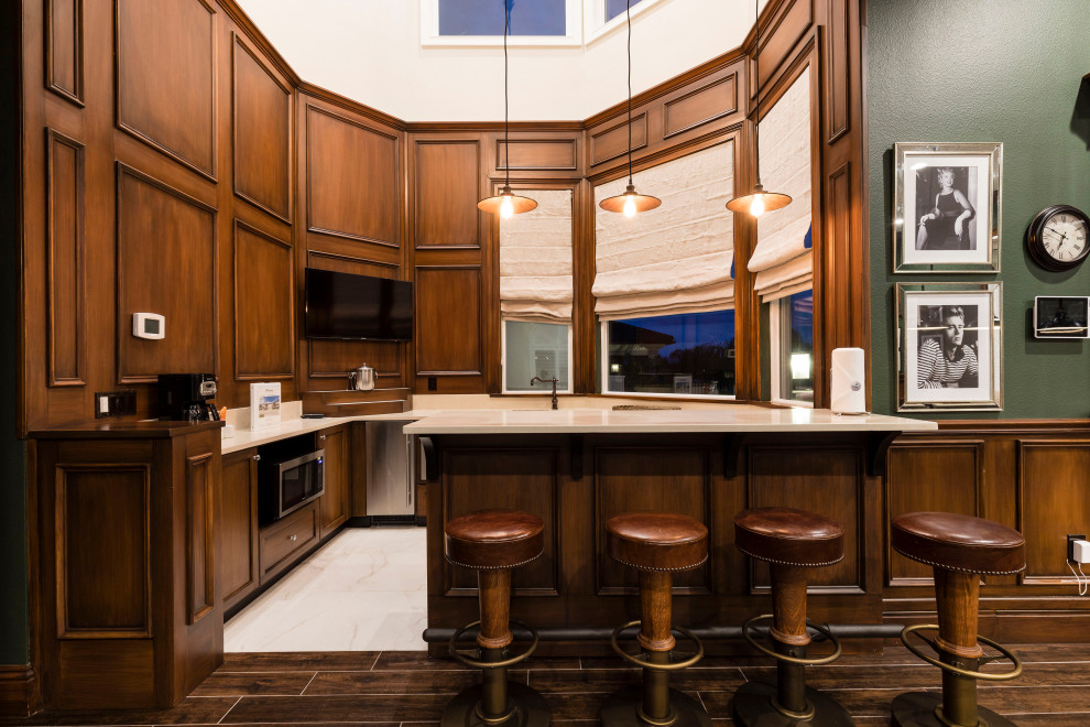 Design ideas for a large traditional u-shaped wet bar in Orlando with an undermount sink, recessed-panel cabinets, medium wood cabinets, quartz benchtops, porcelain floors, white floor and beige benchtop.