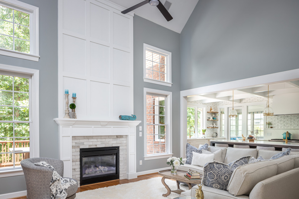 Mittelgroßes, Offenes Klassisches Wohnzimmer mit blauer Wandfarbe, braunem Holzboden, Hängekamin, Kaminumrandung aus Holz, Multimediawand, braunem Boden und gewölbter Decke in Raleigh