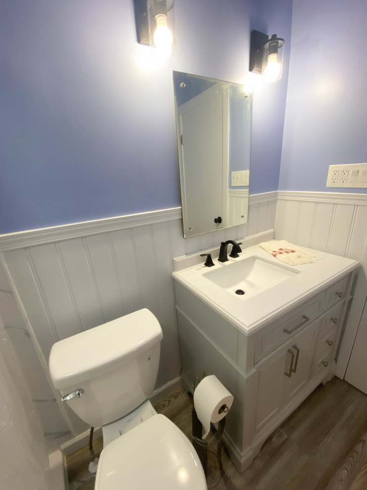 Réalisation d'une petite salle d'eau craftsman avec un placard en trompe-l'oeil, des portes de placard blanches, une douche ouverte, WC séparés, un carrelage gris, un mur bleu, sol en stratifié, un lavabo intégré, un plan de toilette en quartz modifié, un sol gris, une cabine de douche avec un rideau, un plan de toilette blanc, meuble simple vasque, meuble-lavabo sur pied et boiseries.