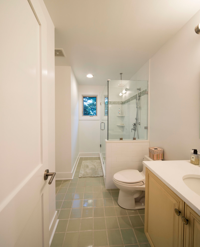 Inspiration for a mid-sized traditional master bathroom in Baltimore with raised-panel cabinets, a corner shower, a two-piece toilet, white walls, porcelain floors, an undermount sink, solid surface benchtops, green floor and a hinged shower door.