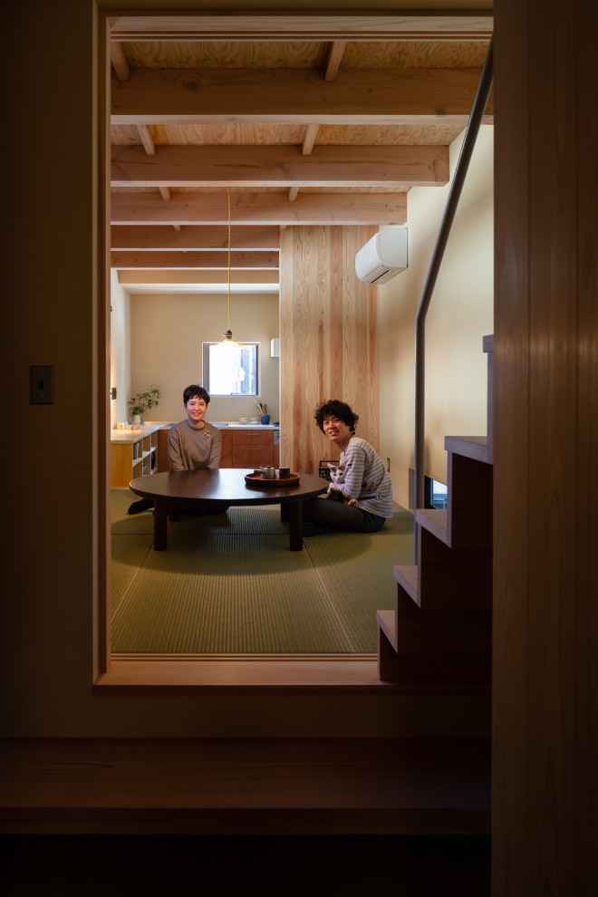 Cette image montre une petite salle à manger ouverte sur le salon en bois avec un mur beige, un sol de tatami et poutres apparentes.