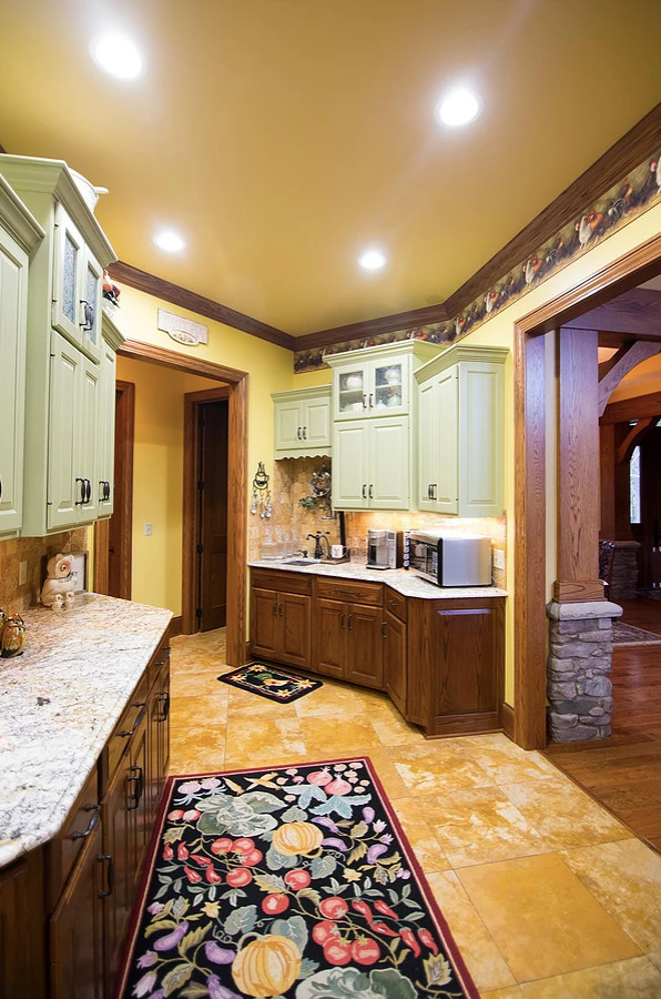 Example of a large mountain style u-shaped porcelain tile and beige floor eat-in kitchen design with an undermount sink, raised-panel cabinets, green cabinets, granite countertops, beige backsplash, porcelain backsplash, stainless steel appliances, an island and multicolored countertops