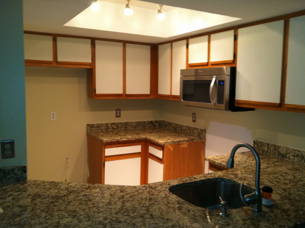 Enclosed kitchen - small transitional porcelain tile enclosed kitchen idea with a double-bowl sink, raised-panel cabinets, dark wood cabinets, granite countertops, multicolored backsplash, stone slab backsplash, stainless steel appliances and no island