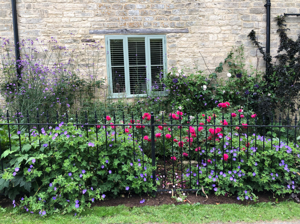 Inspiration for a small farmhouse partial sun front yard mulch and metal fence flower bed in Gloucestershire.