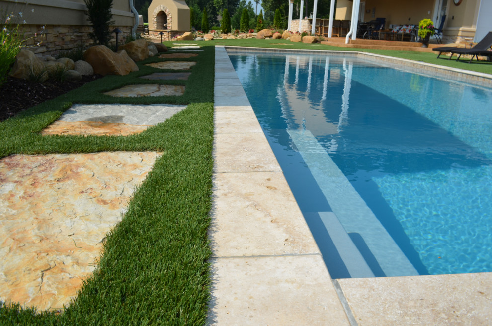 Diseño de piscina mediterránea de tamaño medio rectangular en patio trasero con adoquines de piedra natural